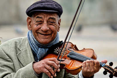 Man smiling as he plays the violin; rent violins here